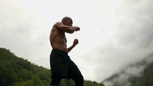 Shirtless Man Boxing Outdoors in Mountain Landscape