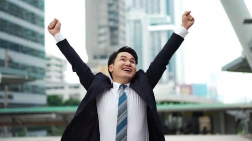 successful business man with arms raised in the city
