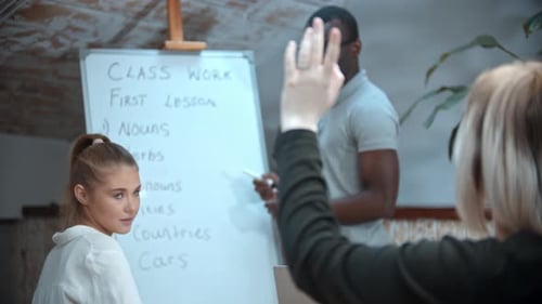 Englischunterricht in der Klasse mit einer schwarzen Lehrerin - Zwei Frauen sitzen am Tisch und eine von ihnen