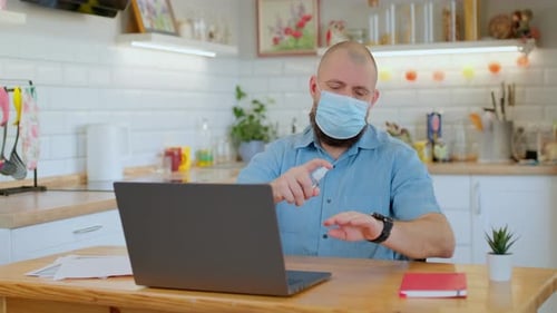 Man Working at Home Using Hand Sanitizer