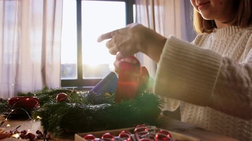 Woman Making Christmas Wreath with Red Ribbon