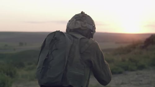 Soldier in Ammunition Walks Across the Field with Rifle at Ready He Examines Area Through Sight Back