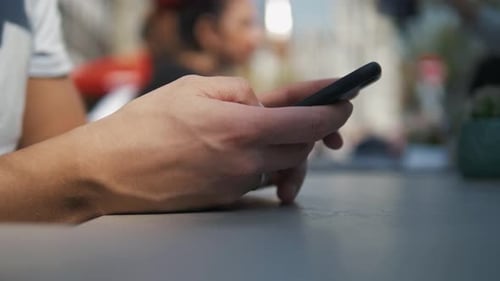Close Up Shot of Man's Hands Use Modern Mobile Phone While Sitting at Outdoor Cafe