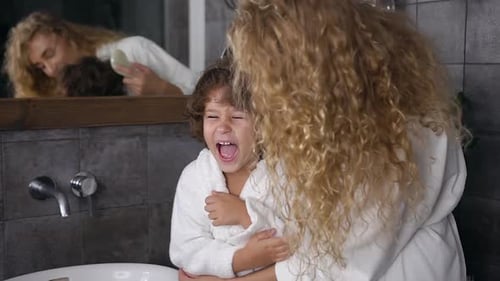 Mother Brushing Smiling Child's Hair in Bathroom