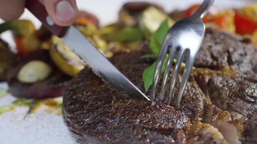 Cutting into Juicy Steak with Roasted Vegetables