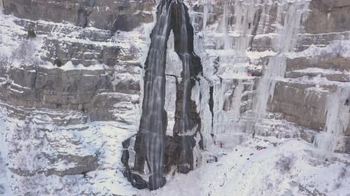 Eiskletterer erklimmen unter extremen Bedingungen einen gefrorenen Wasserfall - zoomen heran