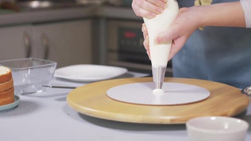 The Pastry Chef Begins to Collect the Cake and Applies the First Drop of Cream