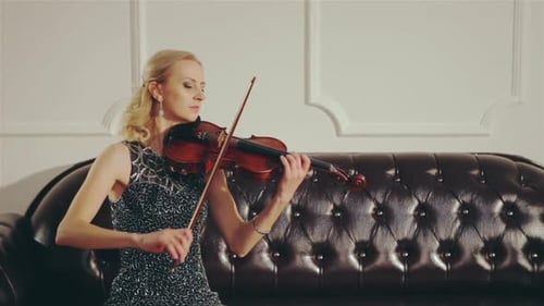 Woman Plays Violin on Couch Elegantly