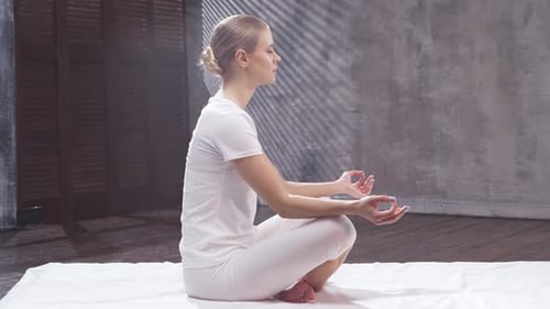 Young and fit woman is practicing yoga indoor in the class. Stretching exercise.