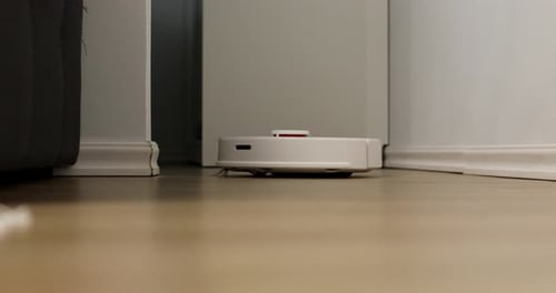 White Robotic Vacuum Cleaner Cleaning Hardwood Floor