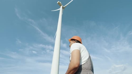 Kompetenter indischer Techniker lächelt Windkraftanlagen im Hintergrund