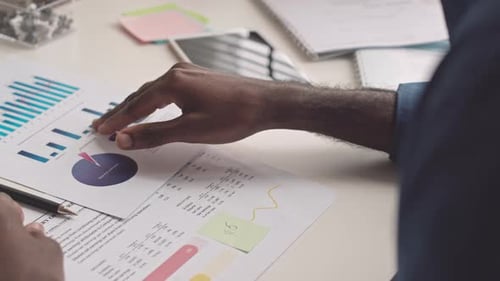 Close Up Hands Using Tablet Above Financial Reports