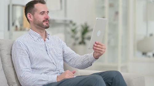 Man on Couch Video Calling on Tablet