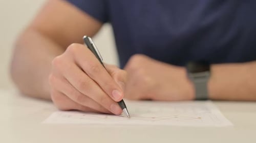 Close Up of Male Hands Reading Report Making Notes