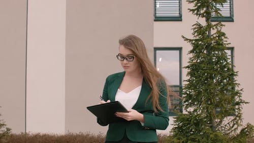 Executive Business Woman with Folder Writing and Doing Paperwork While Looking Around Outdoors