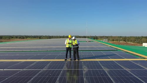 4K Engineer team using drone and tablet maintaining solar cell panels together on building rooftop.