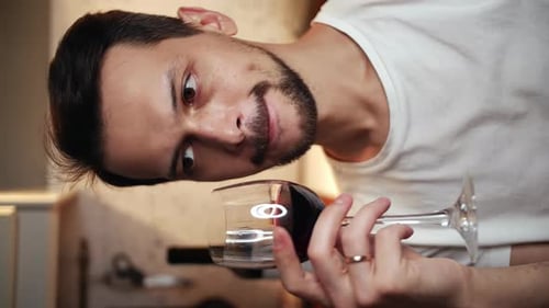 Young Adult Man Examining Glass of Red Wine