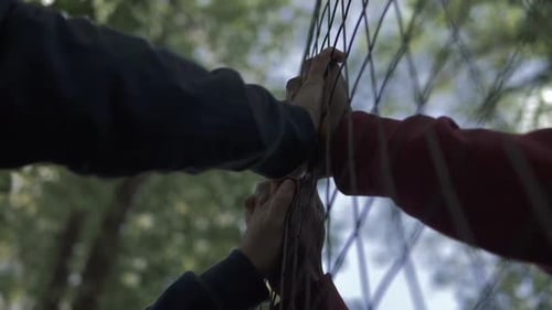verbotene Liebe. Die Hände des schwarzen und weißen Mannes berühren sich durch das Netz