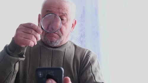 Senior Adult Using Magnifying Glass with Phone