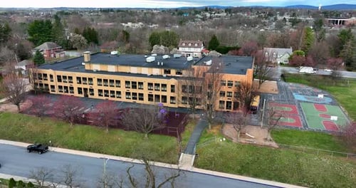 American elementary school building aerial establishing shot with yellow brick building and playgrou