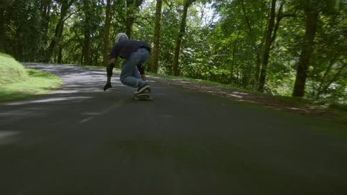 Person Skateboarding Downhill on Rural Paved Road