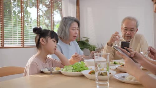 Upset daughter sitting at lunch table looking to addicted parents and grandparents using smartphones