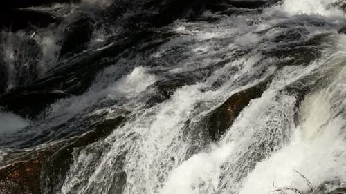 Cascading Waterfall Rushes Over Dark Rocks