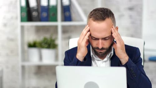 Stressed Businessman Massaging Temples in Office