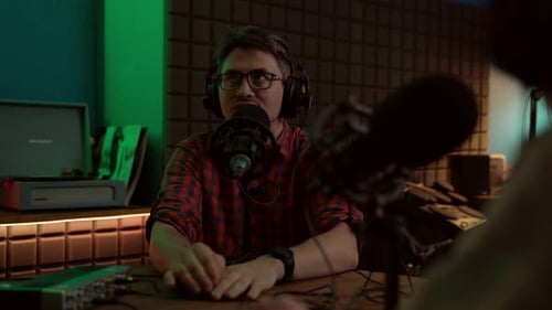 Jeune homme parlant au micro tout en enregistrant un podcast avec un collègue de culture