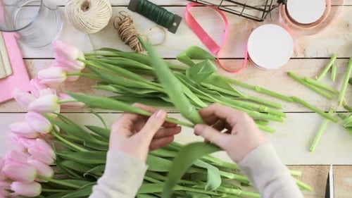 Étape par étape. Fleuriste enveloppant des tulipes roses dans