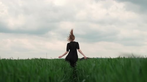 Girl In Black Dress Runs The Field. Romantic Image Of Blonde.