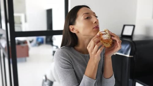 Woman Eating Cream Filled Pastry Indoors