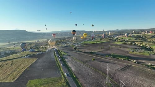 Hot air balloons fly over the mountainous landscape of Cappadocia, Turkey.