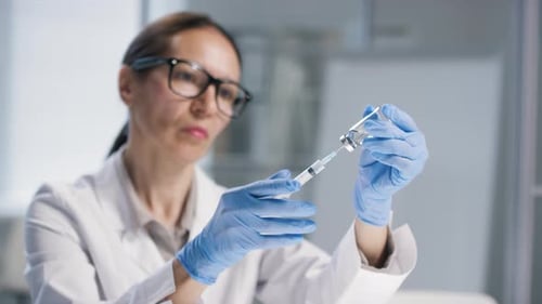 Medical Professional Drawing Liquid into Syringe