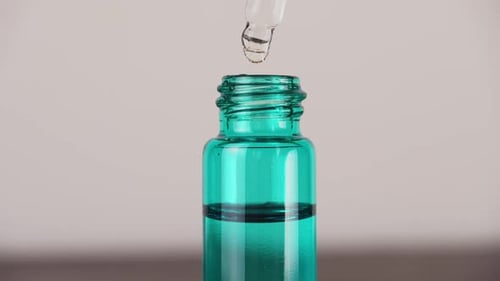 Liquid Drops from Dropper into Teal Bottle