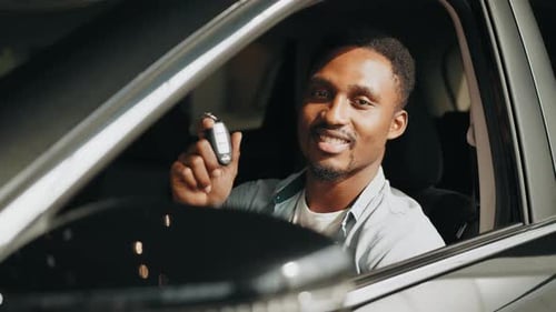 Man Smiling in Car Holding Up Keys