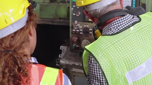 Gruppe von Fabrikarbeitern, die Maschinenausrüstung in der Fabrikwerkstatt verwenden
