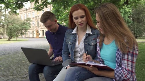 Studentin schreibt in ihr Übungsbuch auf dem Campus