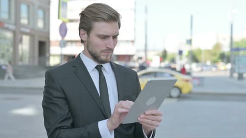 Young Businessman Using Tablet Outdoors in Urban Setting