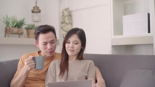 Smiling Couple Using Laptop on Gray Couch