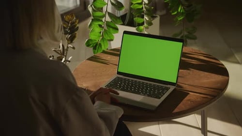 Handheld Shot of an Unrecognisable Caucasian Woman Watching a Laptop Computer with Green Screen