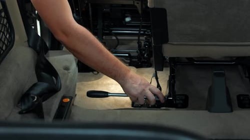 Hand Using Wrench to Repair Car Seat