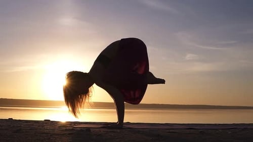 Yoga Bakasana Crane Pose von einer Frau in Silhouette mit Dunst-Sonnenuntergangshimmel im Hintergrund