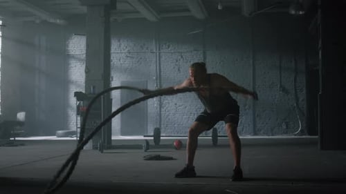 Man Working Out with Battle Ropes in Gym