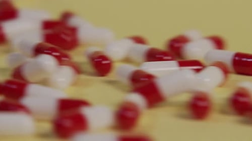 Slow motion close-up of a single pill as several pills roll by and push it out of frame.