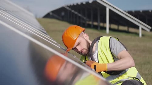 Male Engineer in a Uniform Is Checking the Solar Battery Outside