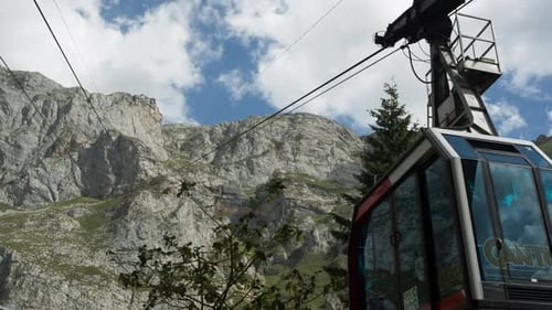 Cable Car Ascending Rocky Mountain on Sunny Day