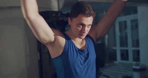 The Athlete Doing Circular Movements of Arms and Tilts Head in Gym