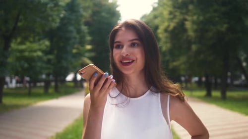 Woman Using Phone in Park on Sunny Day