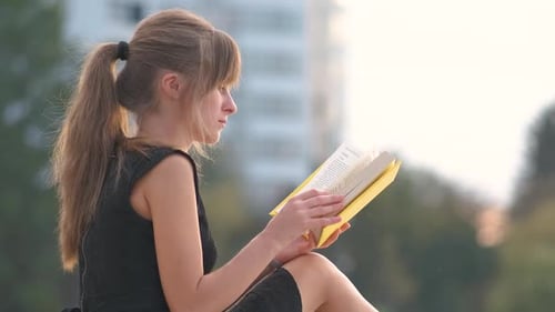 Female Student Sitting in Summer Park Reading Textbook Outdoors